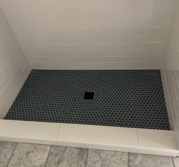 An offset tile pattern installed as shower backsplash and mini hexagonal patterned tiles for the flooring