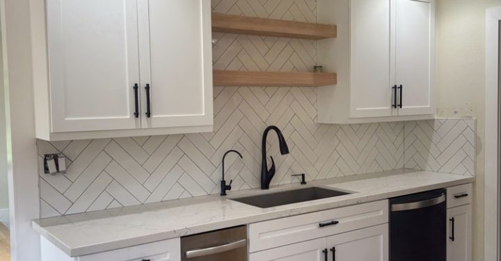 Chevron tile backsplash installed in the kitchen with wall mounted wood shelves in between cabinets