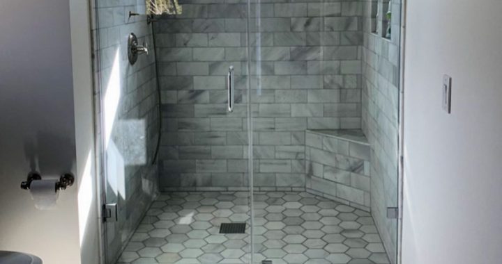 A bathroom with floors upgraded with hexagon tiles, and shower backsplash in offset pattern tiles