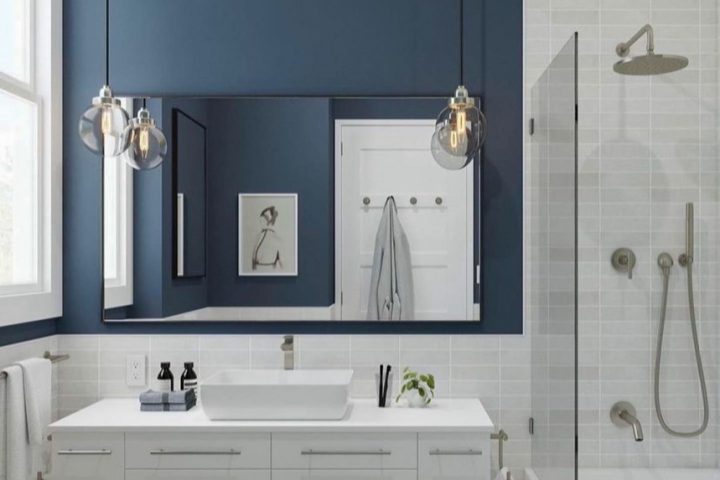 A remodeled bathroom with a shower area having a glass partition, a storage cabinet with sink on top, and a tiled backsplash and flooring